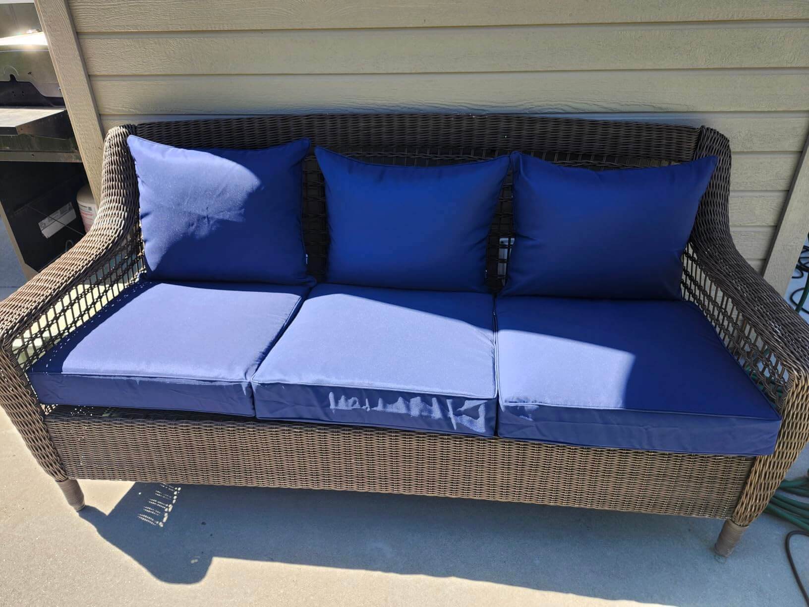 Wicker outdoor sofa with Favoyard blue bench cushions on a patio