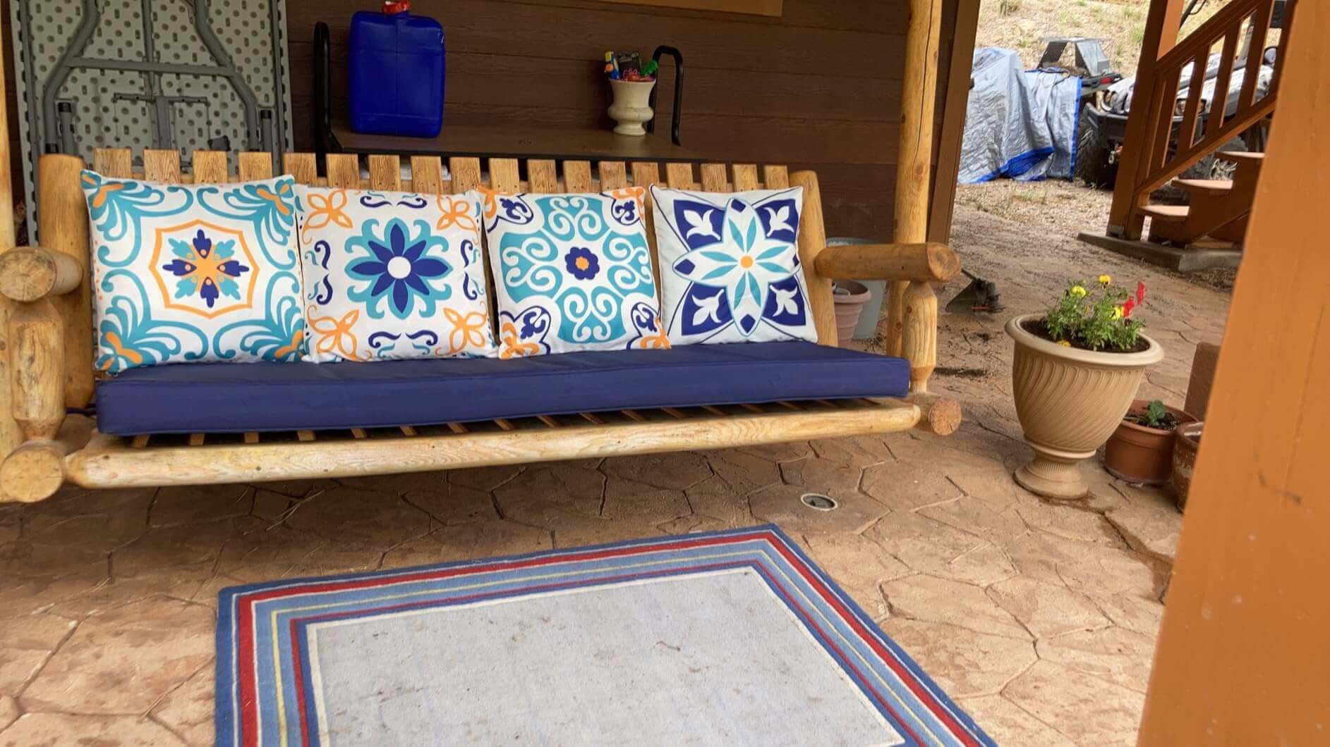 Wooden bench with colorful patterned Favoyard outdoor cushions on a patio