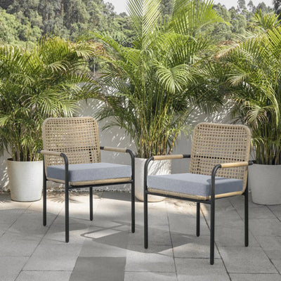 Two wicker chairs with cushions on a patio surrounded by potted plants.